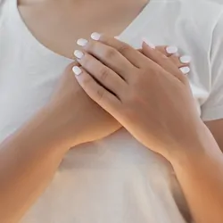 A woman places her palms one over the other on her left breast