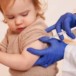 A clinician in PPE vaccinates a child.