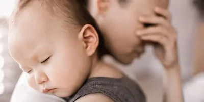 A woman feels sad and tired as she holds a baby.