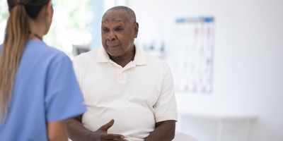 An African senior gentleman speaks with a clinician during a routine check-up in the doctor's office.