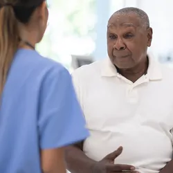 An African senior gentleman speaks with a clinician during a routine check-up in the doctor's office.