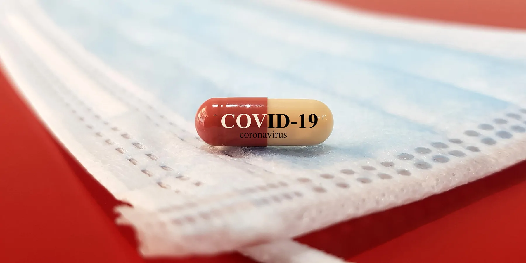 A drug capsule for COVID-19 rests on a clean surgical face mask.