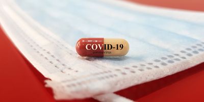A drug capsule for COVID-19 rests on a clean surgical face mask.