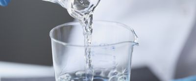 Water pouring from a beaker into small glassware.