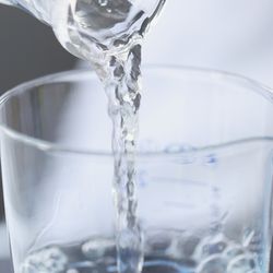 Water pouring from a beaker into small glassware.