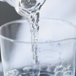 Water pouring from a beaker into small glassware.