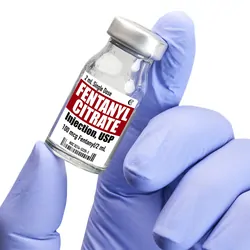A gloved hand holding a Fentanyl in vial against white background.