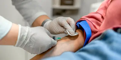A Nurse draws blood from a patient's arm in the medical clinic.