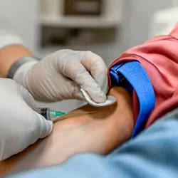 A Nurse draws blood from a patient's arm in the medical clinic.