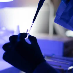 Photo of a clinical lab professional pipetting a PFAS sample in the lab.