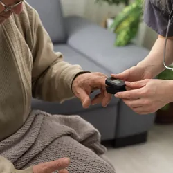 A nurse uses a pulse oximeter to check a male patient's oxygen at home.