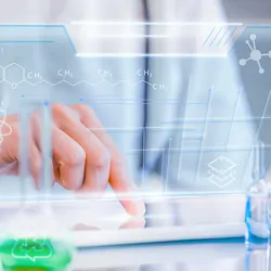 A researcher surrounded by lab glassware touches a digital tablet as vectors of clinical chemistry and physics appear in foreground.