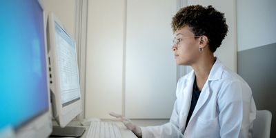 Black female clinical laboratory professional sitting at a computer analysing genomic data.