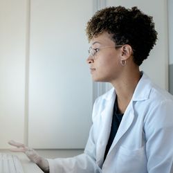 Black female clinical laboratory professional sitting at a computer analysing genomic data.