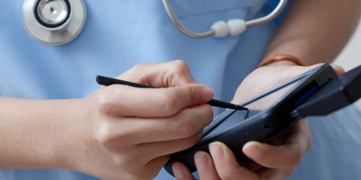 A clinician uses a digital handheld device with a stylus.