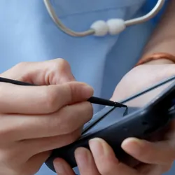 A clinician uses a digital handheld device with a stylus.