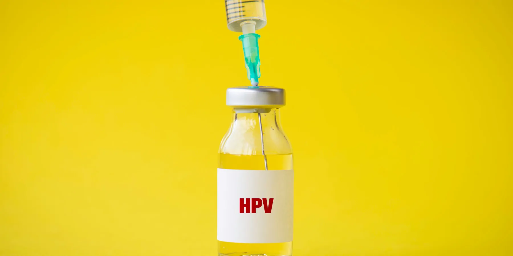 E. coli-Produced HPV Vaccine Proves to Be Safe in Phase 2 Trial HPV vaccine vial with a syringe in it to load against a yellow background.