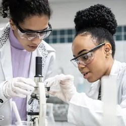 Two female students using the microscope in the laboratory.