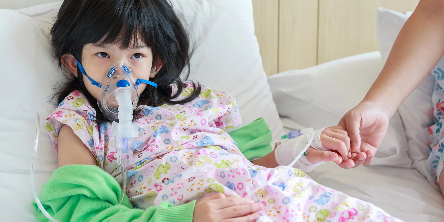 A sick little girl has a nebulizer mask on for respiratory treatment.