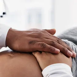 Photo of a pregnant Black person getting a prenatal checkup.