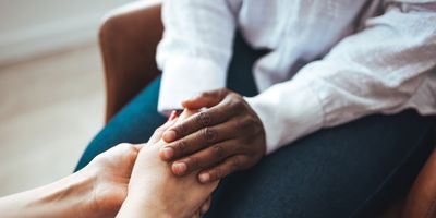 A psychologist holds the palms of a female patient in comfort.