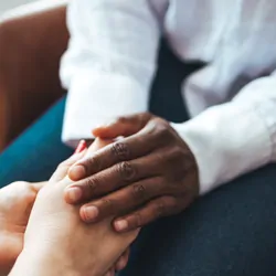 A psychologist holds the palms of a female patient in comfort.