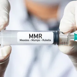 A pair of gloved hands holding a syringe labeled Measles, mumps, and rubella (MMR).