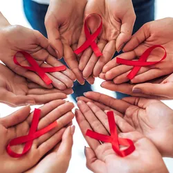 A group of hands holding red ribbons in support of HIV/AIDS awareness.