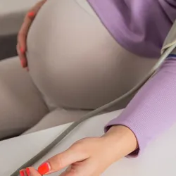 A pregnant person's left has a blood pressure-measuring sleeve as a stethoscope measures their blood pressure to check for preeclampsia.