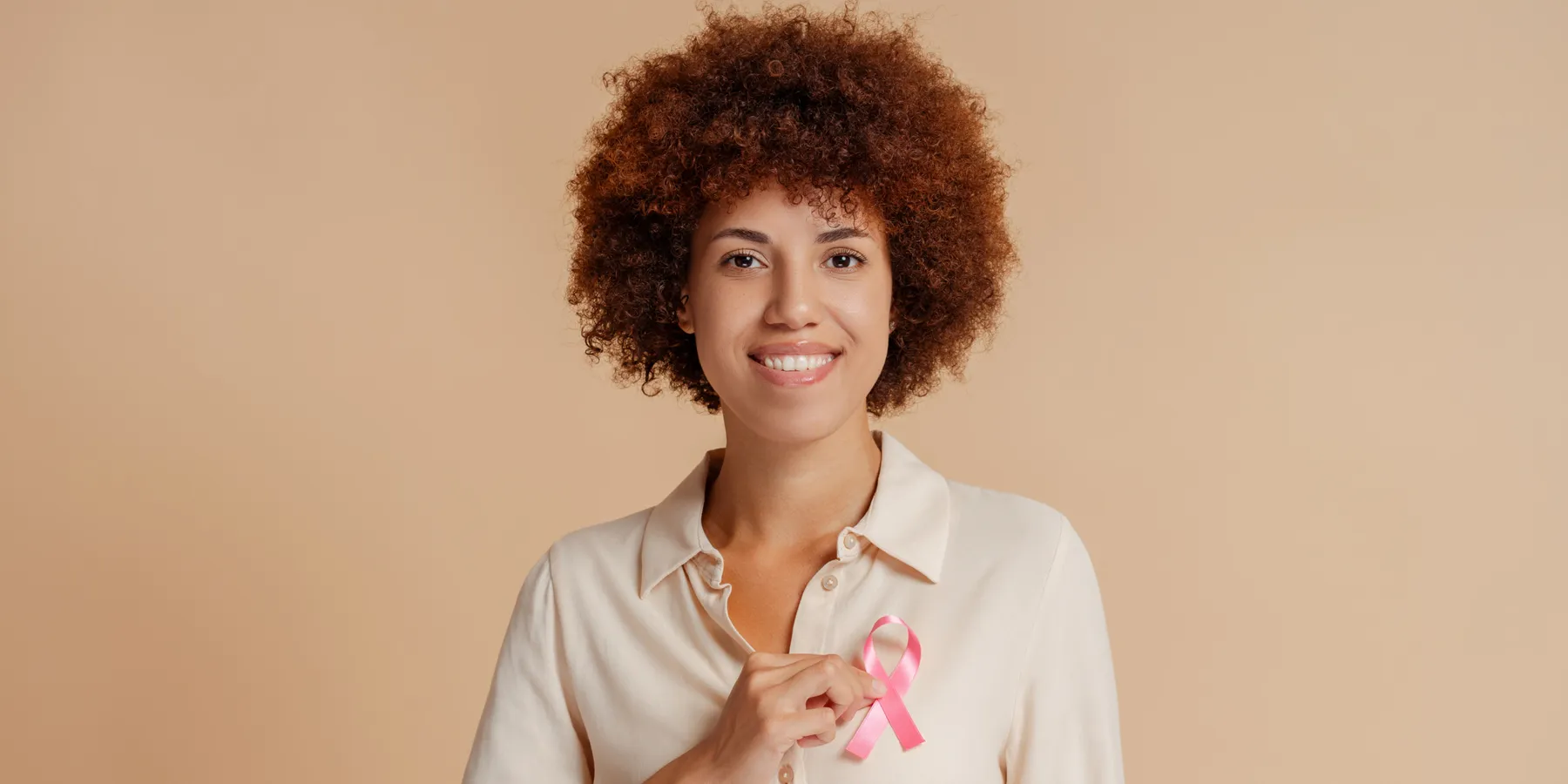 Drug Combo Could Benefit HER2-Positive Breast Cancer Cases An African-American woman holding a pink ribbon on her left breast marking breast cancer awareness.