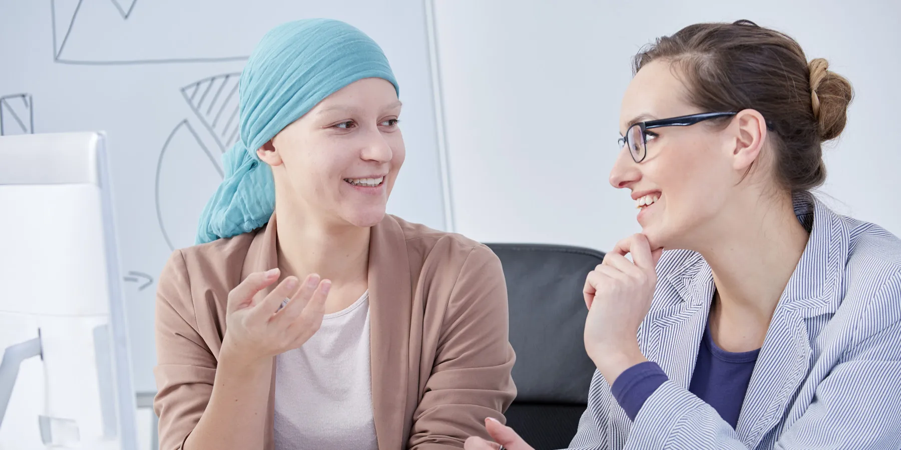 A smiling female cancer patient talking to her doctor.