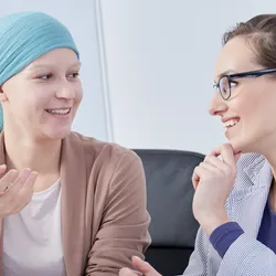 A smiling female cancer patient talking to her doctor.