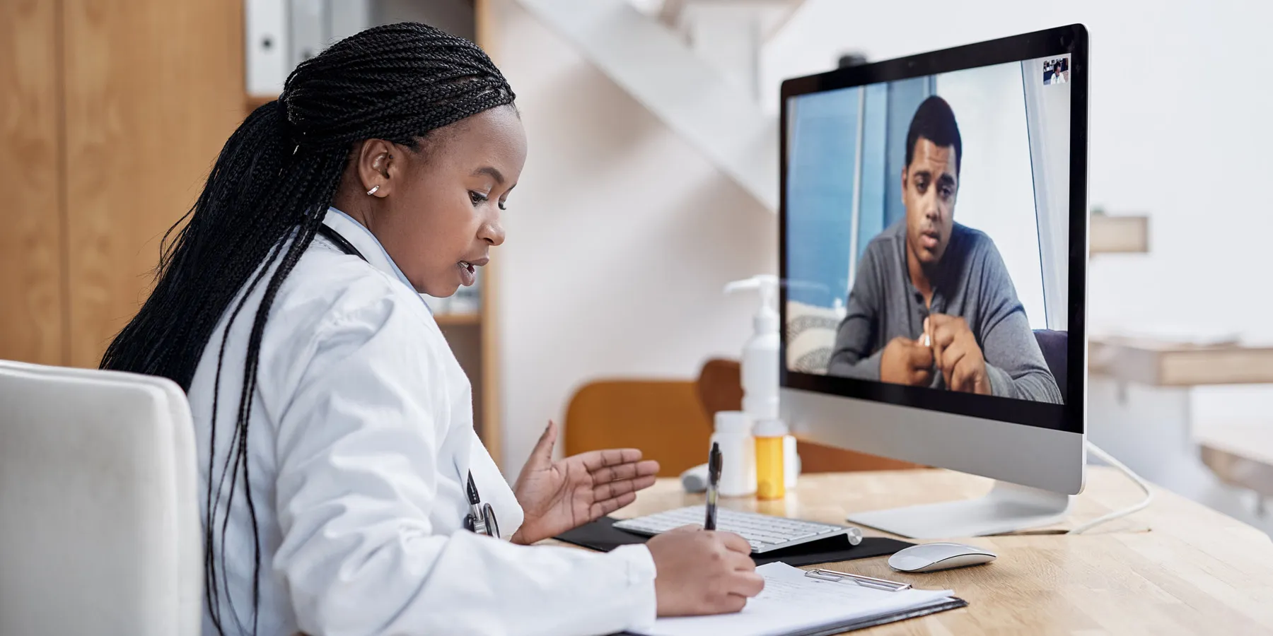 Remote Consent Options Enhance Clinical Trial Accessibility Shot of a young female clinician writing notes during a video call with a male patient.