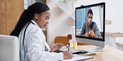 Shot of a young female clinician writing notes during a video call with a male patient.