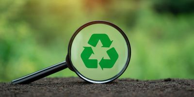 Recycling symbol in magnifying glass on nature background.