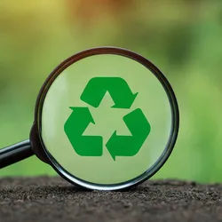 Recycling symbol in magnifying glass on nature background.