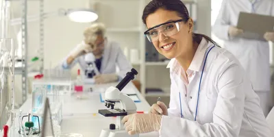 Laboratory technician using a microscope to analyze patient data.