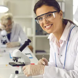 Laboratory technician using a microscope to analyze patient data.