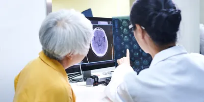 Doctor reviewing brain scans with patient discussing blood-based biomarkers for Alzheimer's disease
