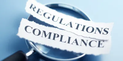Magnifying glass over text showing regulations and compliance