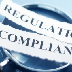 Magnifying glass over text showing regulations and compliance