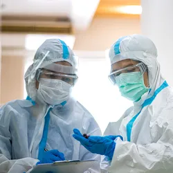 Laboratory workers in protective gear discussing precautions