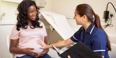 A pregnant woman is being checked by a nurse.