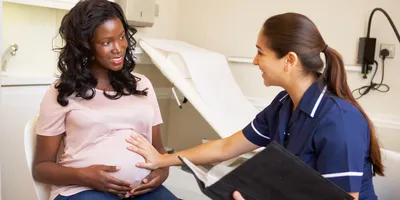 A pregnant woman is being checked by a nurse.