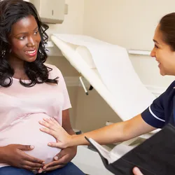 A pregnant woman is being checked by a nurse.