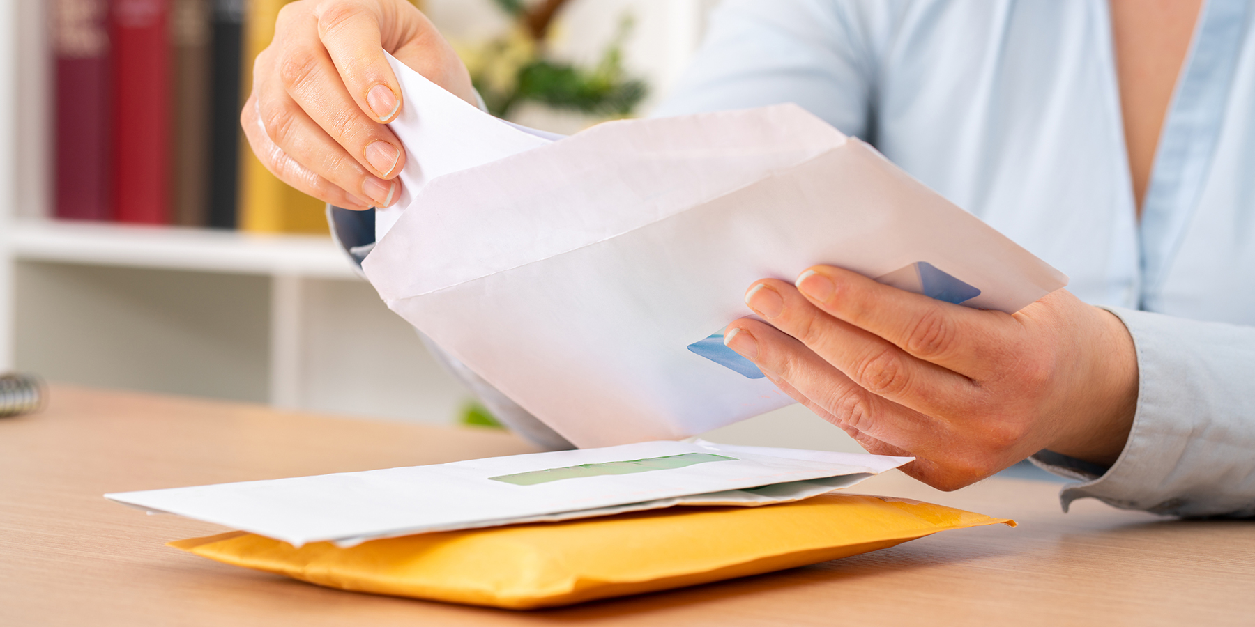 mailed-outreach-nearly-doubled-liver-cancer-screening-rates Close-up of a person taking a letter out from an envelope on a desk at home or office.