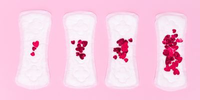 Four sanitary napkins with an increasing number of heart-shaped confetti are arranged in tandem on a pink background.