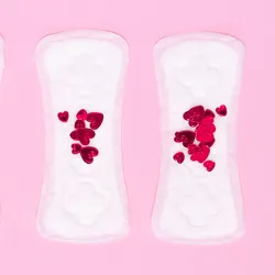 Four sanitary napkins with an increasing number of heart-shaped confetti are arranged in tandem on a pink background.
