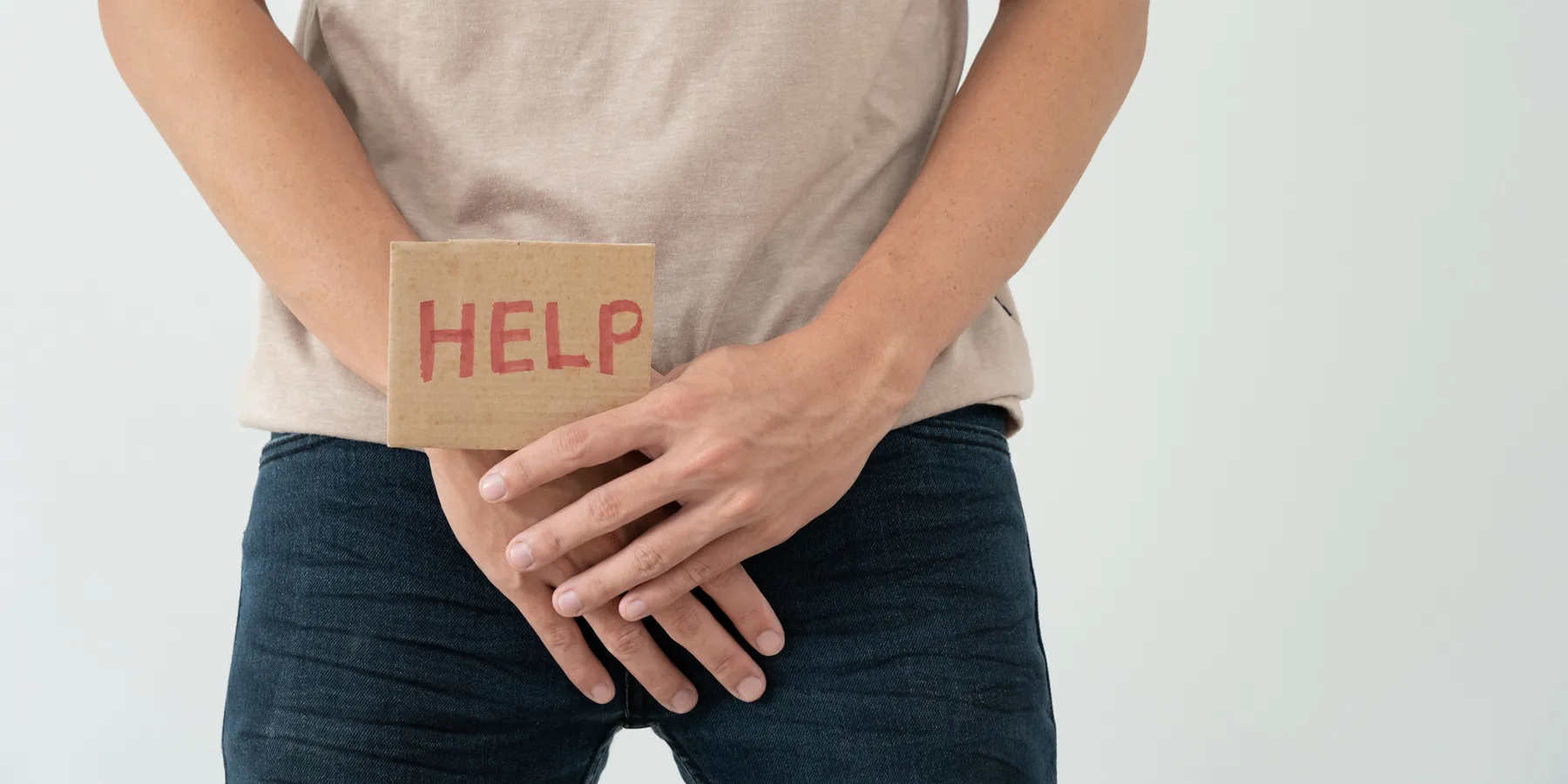 combination-hormone-therapy-may-delay-cancer-progression A man holds hands in front of his groin, showing a card with HELP written on it.