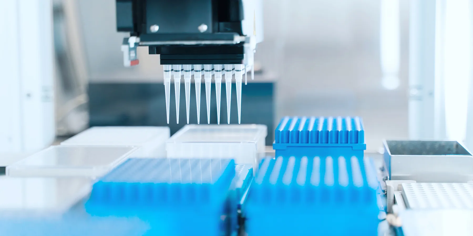 An automated liquid handling system picks microtips from tip boxes to aspirate a reaction component.